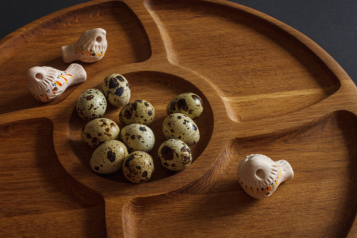 Quail eggs with a toys birds on a wooden plate