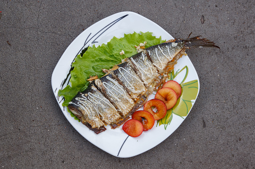 Baked mackerel with green lettuce and fruit. Close-up. View from the top