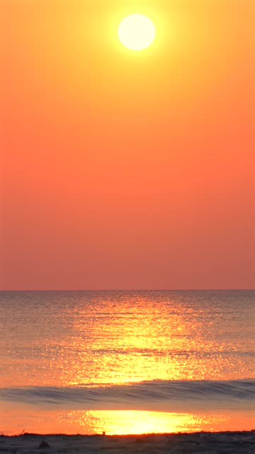 Vibrant sunrise over tranquil ocean with golden sunlight reflecting
