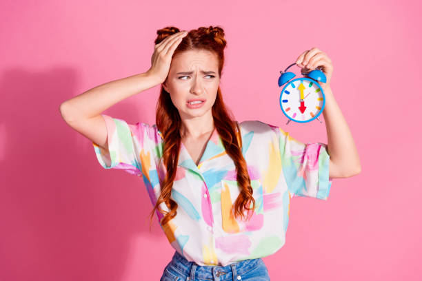 foto de menina confusa sem noção vestida blusa colorida olhar no relógio esqueceu sobre venda palma na cabeça isolada no fundo da cor rosa - shirt problems red pink - fotografias e filmes do acervo