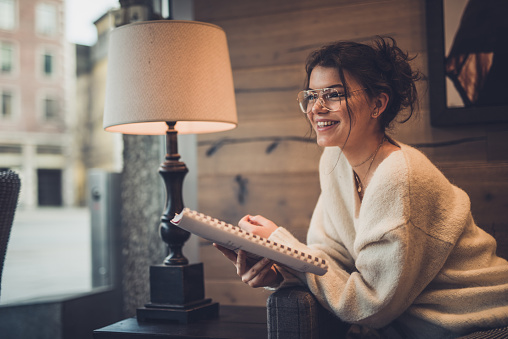Smiling woman in a white sweater enjoys reading