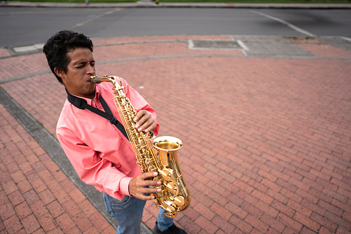 Mid adult man playing saxophone outdoors