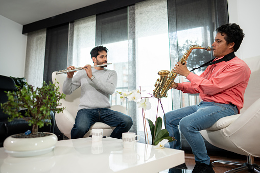 Friends playing flute and saxophone together at home