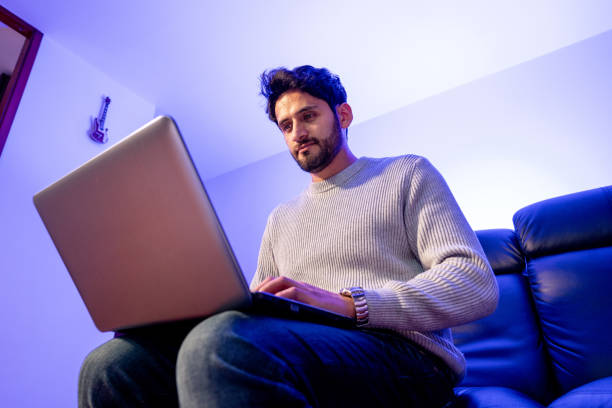 istock Mid adult man using laptop at home 2148723278