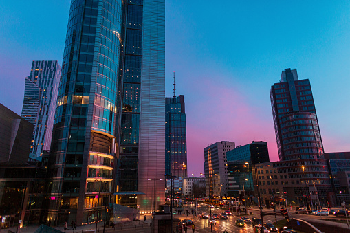 Beautiful modern city of Warsaw with buildings and road on the evening sunset sky with blue and pink light. Poland