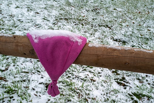 children's cap on the fence in winter, snowed in