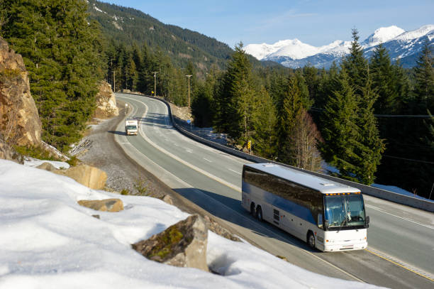 Bus travels down Sea to Sky mountain highway, snowy patches in foreground
