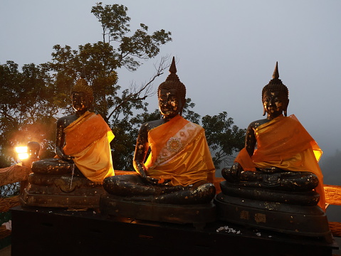 The three Buddha statues during sunset sitting on top of the mountain in Khao Khitchakut National Park located in Chanthaburi of Thailand