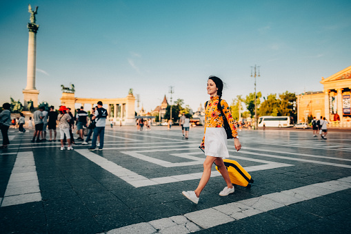 Woman with suitcase just arriving in Budapest and walking through Hero’s square