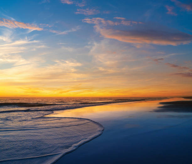 Beautiful sunset on the beach with golden and blue sky in water reflection