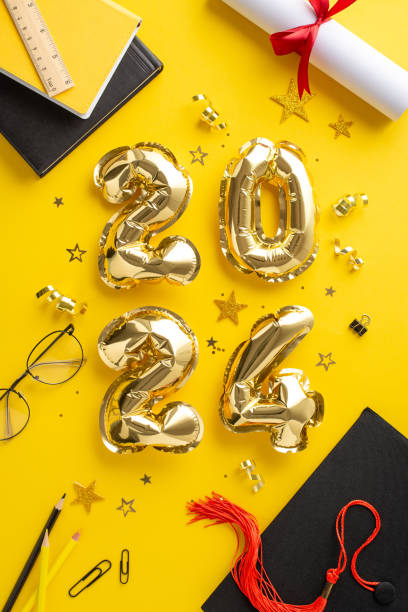 istock Academic milestone setting. Overhead vertical photo displaying 2024 radiant balloons, graduation cap, diploma adorned with ribbon, academic essentials, glasses, dazzling confetti on yellow backdrop 2148726103