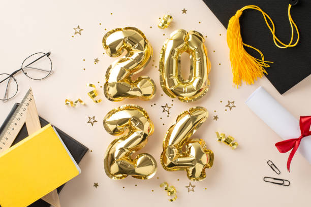 Graduation theme. Top view of 2024 reflective balloons, academic cap, diploma, learning tools, stationery, reading materials, eyewear, shiny confetti on pastel beige background