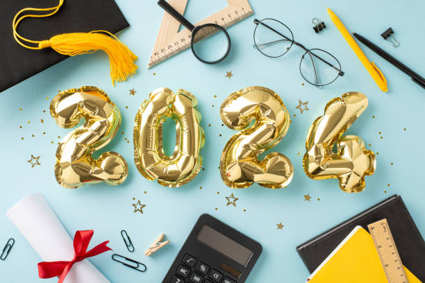 istock Commemorative setting: Top view of shimmering gold balloons, cap, diploma, study materials, books, pens, clips, calculator, rulers, magnifying glass, glasses, confetti, tinsel on pale blue base 2148726114