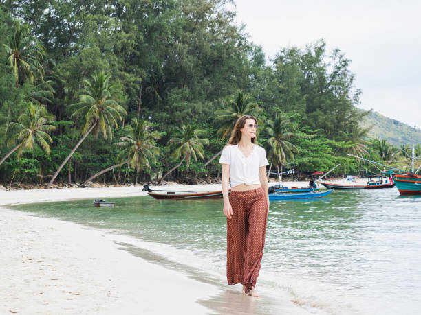 istock Cute woman walking along a stunning white sandy beach 2148727537