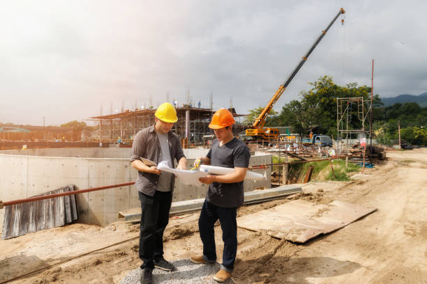 istock Team of construction workers discussing project details with blueprint in construction site. 2148729428