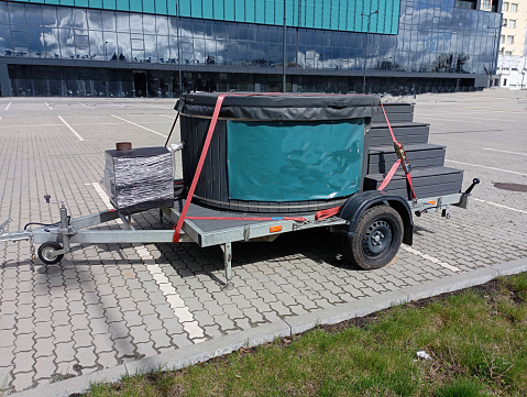 A portable tub for bathing and relaxation on a car trailer in the parking lot in front of a modern building.