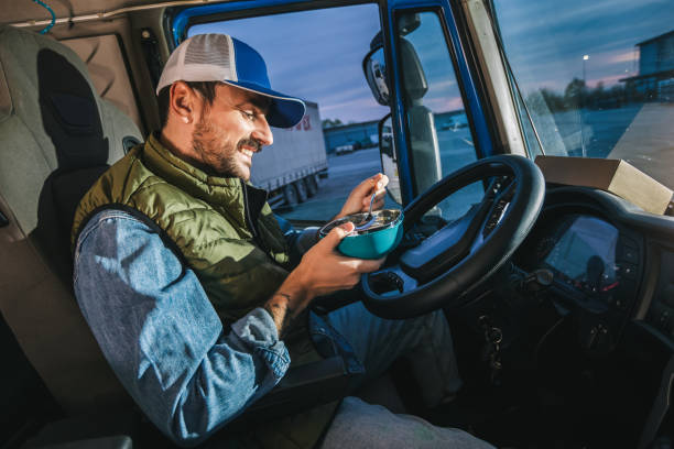 istock Truck driver taking a break from long drive to eat some food from container. 2148732557