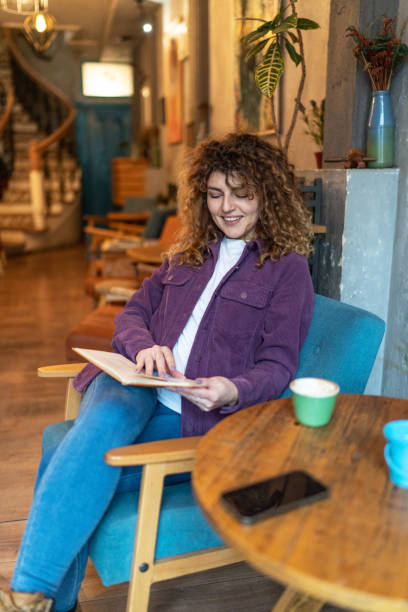 istock Young woman drinking coffee and reading a book in a cafe 2148732756