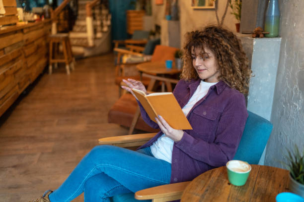 istock Woman in cafe reading a book 2148733140