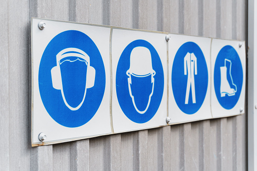 Prescriptive safety signs and posters of personal protective equipment at work. Headphones, helmet, workwear, safety shoes in a row