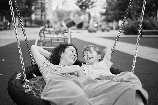 Happy Young mother playing with her son on the playground, hugging, laughing. having fun together on the weekend sunny day. School playground. High quality photo