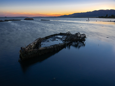 Old boat abandoned and sunken off the coast with a fisherman's net in it.