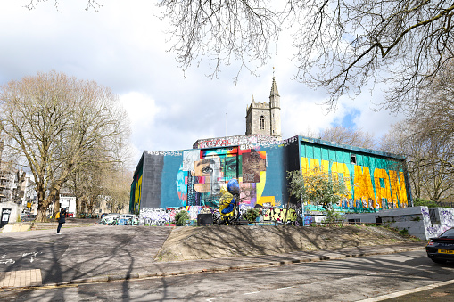 Bristol, England- March 29, 2024: Street art in the old city of Bristol. St. Mary Le Port Church in the background.