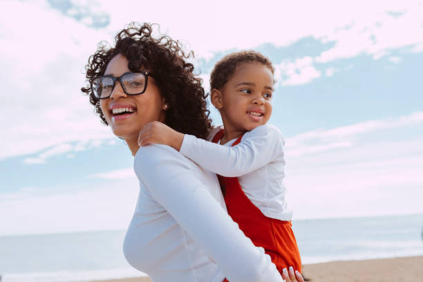 istock Mother and her daugther enjoying together piggyback on beach 2148737086