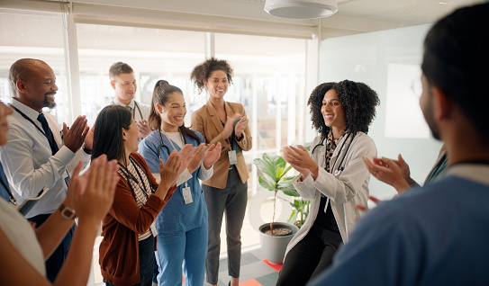 Doctor, coach and applause with team in meeting for collaboration, conference or health workshop at office. Medical professional. manager or leader clapping with employees for success at workplace
