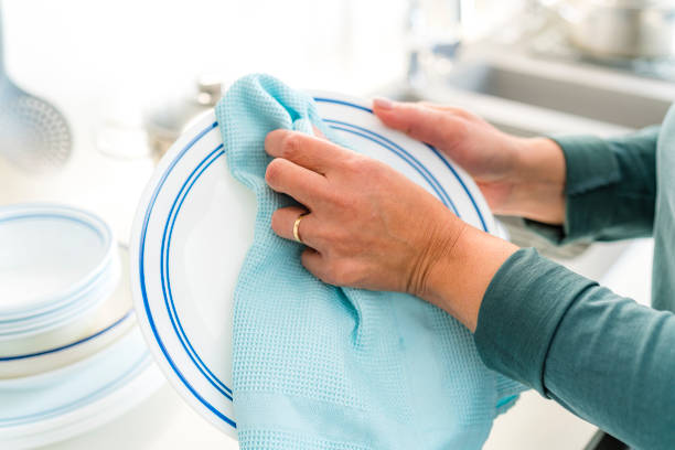 Woman wiping dishes with a kitchen towel. High resolution 42Mp indoors digital capture taken with SONY A7rII and Zeiss Batis 40mm F2.0 CF lens