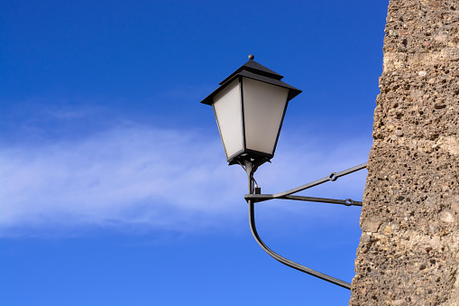 Background with wall-mounted street lamp during daytime on blue sky in horizontal format
