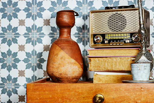 old retro vintage radio above books with clay bottle on wood table