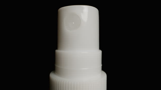 White spray bottle with a push spray nozzle. Close-up on a black background.