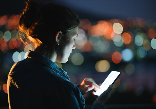 Outdoor, night and woman with smartphone, screen and typing with digital app and texting a contact. City lights, evening or email with person, message or cellphone with social media, tech or internet