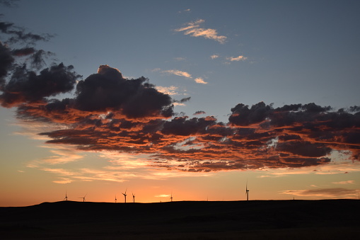 Glorious sunrise in Colorado with fluffy clouds and wind turbines silhouetted on the horizon