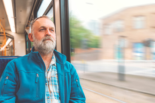 happy bearded man in blue warm jacket on a bus or tram. Lifestyle concept