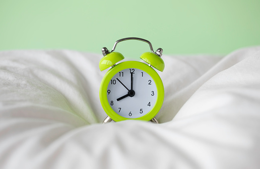 Green alarm clock on the bed.