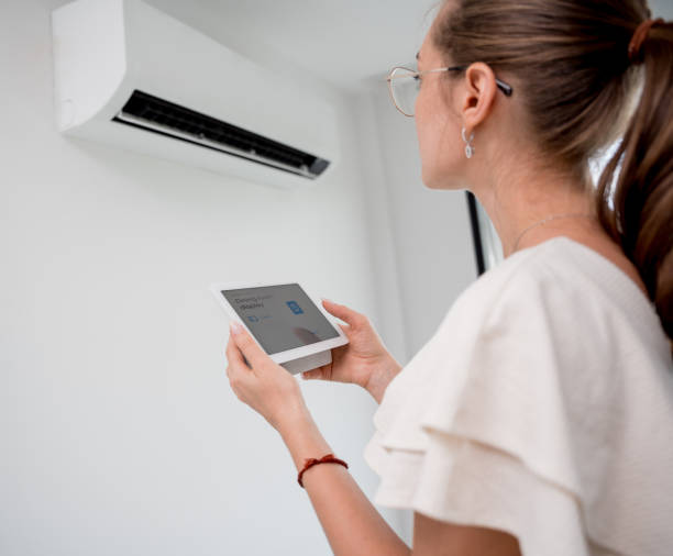 istock Young woman operates wireless aircon system in a modern apartment. 2148746365