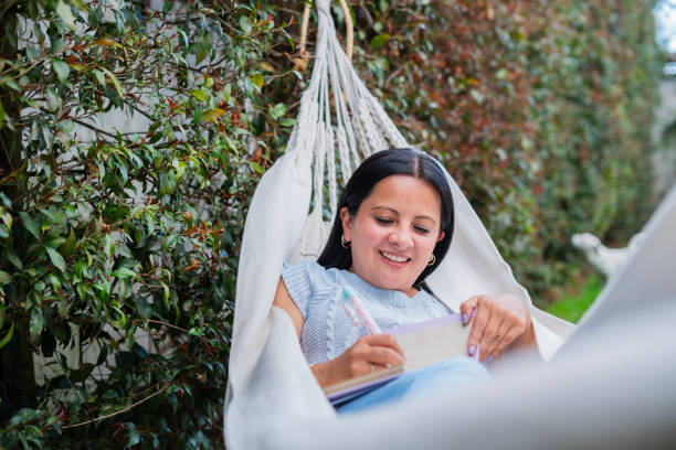 istock latin woman smiling writing in her hammock 2148747367