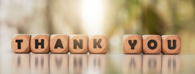 Thank you phrase on wooden blocks on glass background with reflection.Stock photo