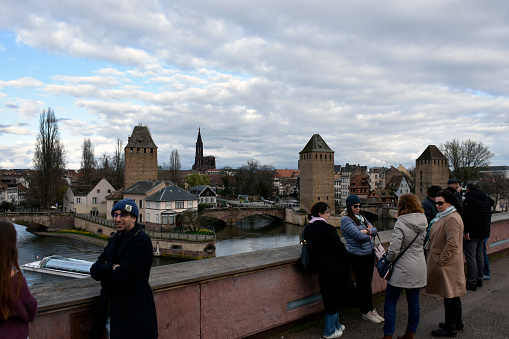 Strasbourg, France - March 16, 2024: Ponts Couverts, Strasbourg, Strasbourg River Ill Tour Boat, Building Exterior, People Walking, Standing, Taking Picture During Springtime Scene And More