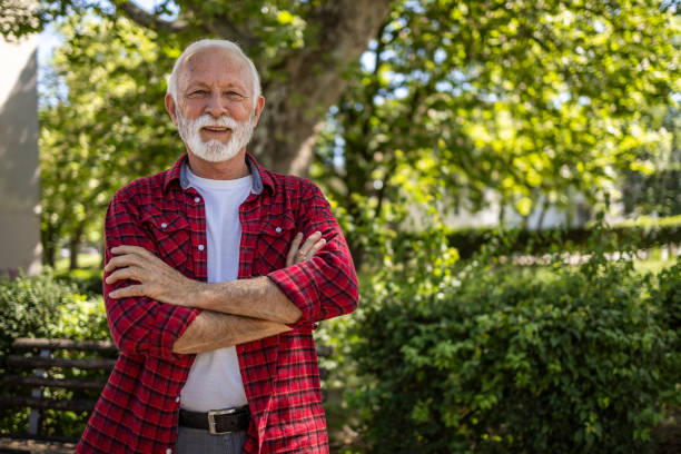 istock An elderly man stands in the park with his arms crossed 2148748090