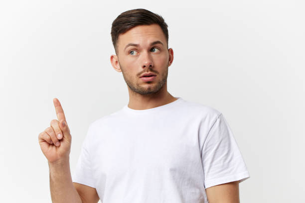 istock Eureka offer. Excited tanned handsome man in basic t-shirt point finger up look aside posing isolated on over white studio background. Copy space Banner Mockup. People emotions Lifestyle concept 2148748357