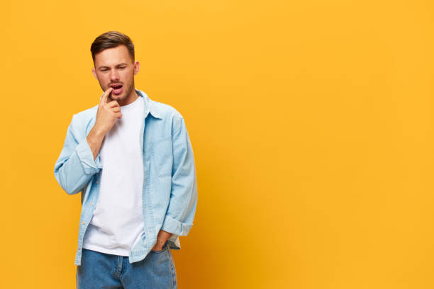 istock Thoughtful troubled with problems tanned handsome man in blue basic t-shirt touch chin posing isolated on orange yellow studio background. Copy space Banner Mockup. People emotions Lifestyle concept 2148748429