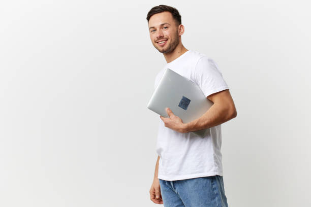 istock Smiling happy tanned handsome man in basic t-shirt hold laptop pc smile at camera posing isolated on over white studio background. Copy space Banner Mockup. Electronics repair concept 2148748629