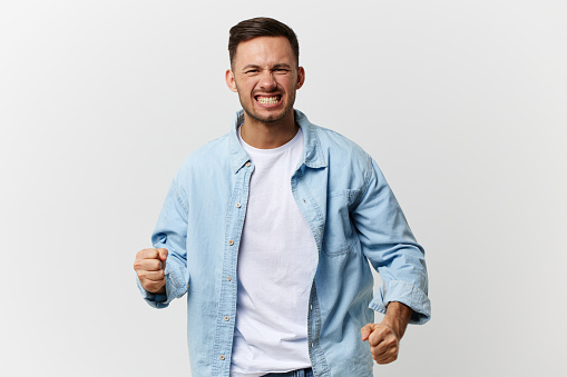 Angry irritated tanned handsome man in blue basic t-shirt scream growl at camera posing isolated on white studio background. Copy space Banner Mockup. People emotions Abusive relationships concept