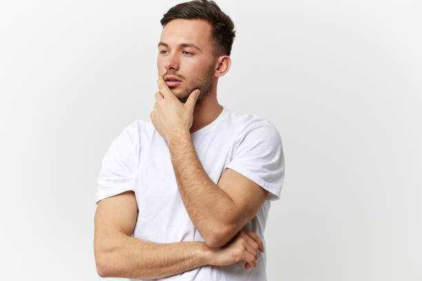 istock Pensive thoughtful sad tanned handsome man in basic t-shirt touch chin look aside posing isolated on over white studio background. Copy space Banner Mockup. People emotions Lifestyle concept 2148748846