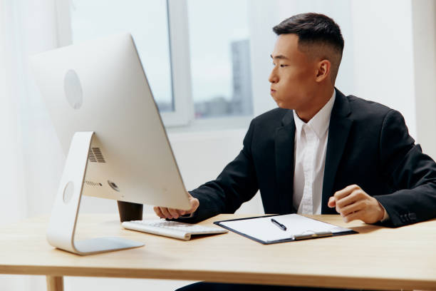 istock Asian man sitting at a desk in front of a computer Lifestyle 2148749183
