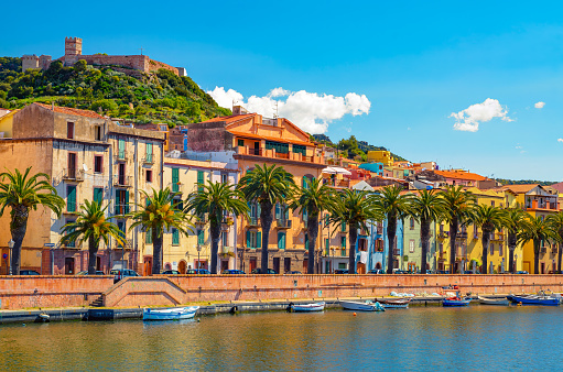 Picturesque view of Bosa town along Temo River in Sardinia, Italy, with Castle of Serravalle, colorful buildings and palm trees