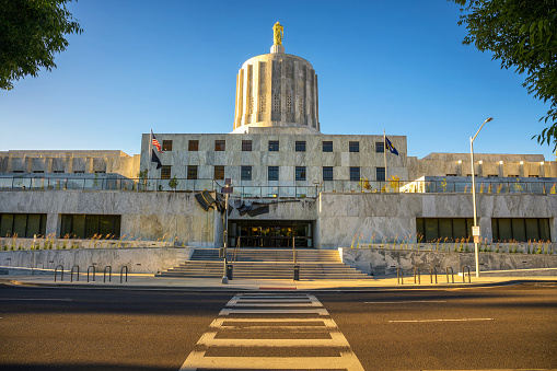 Oregon State Capitol in Salem with a clear blue sky. It is distinguished by its Art Deco architecture and the Oregon Pioneer statue atop its dome.